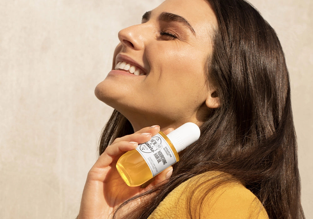 woman holding glossy hair oil and smiling