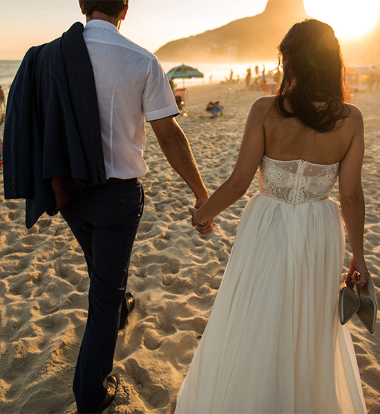 Wedding couple walking on a beach towards the setting sun