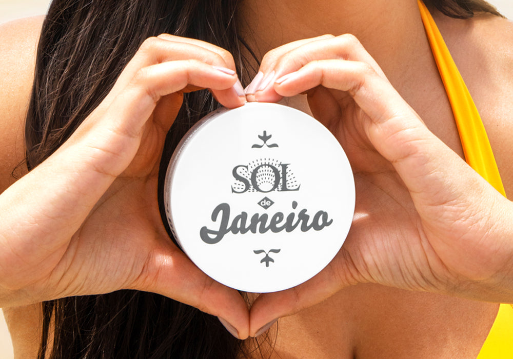 woman holding a jar of Sol de Janeiro Brazilian Bum Bum Cream with her hands shaped like a heart