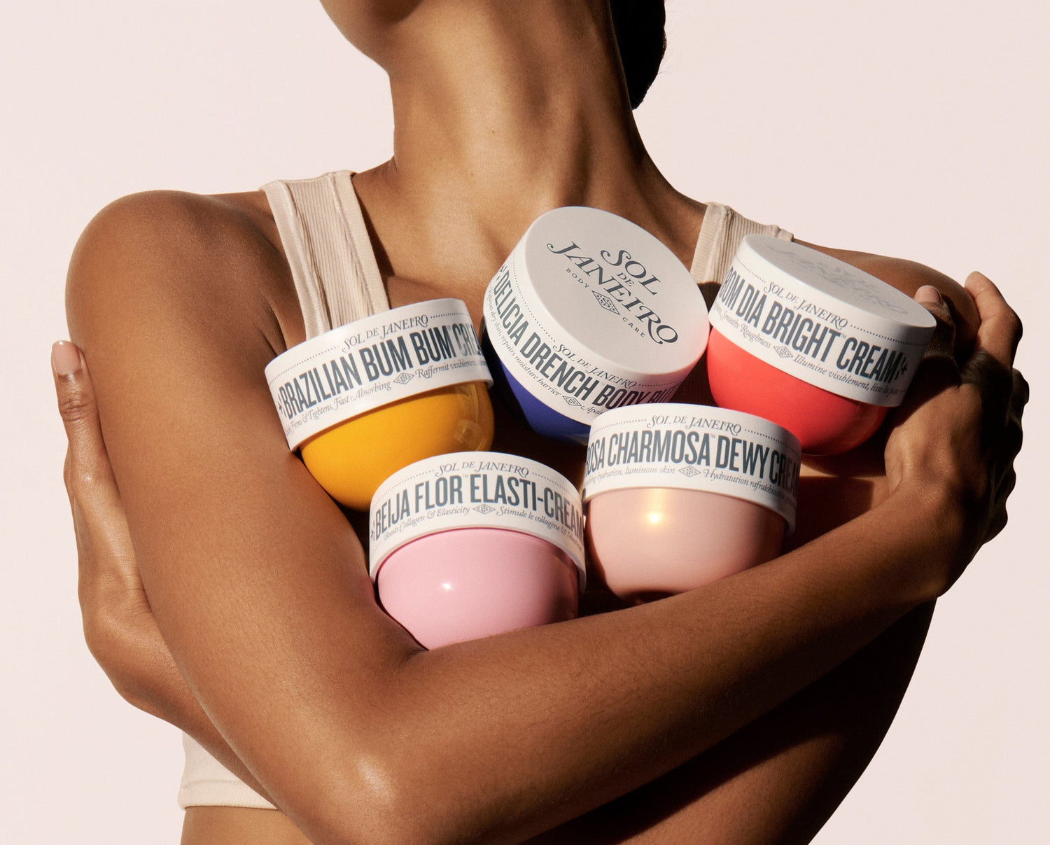 sol de janeiro body creams being held by model
