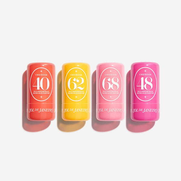 Four cylindrical cosmetic tubes in coral, yellow, pink, and magenta, arranged in a row on a light gray background. Each tube has a white oval label with numbers 40, 62, 68, and 48, and the brand name Sol de Janeiro is visible near the bottom.