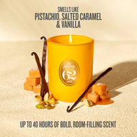 A yellow jar candle with a visible flame and a circular 'Joe Janeiro Scents 62' label, styled with vanilla pods, caramel cubes, and pistachios on a warm beige surface. Text above reads 'SMELLS LIKE PISTACHIO, SALTED CARAMEL & VANILLA' and text below reads 'UP TO 40 HOURS OF BOLD, ROOM-FILLING SCENT'.