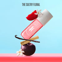Pink bottle with white cap on a red fruit and vanilla bean against a light blue background, labeled 'The Sultry Floral'.