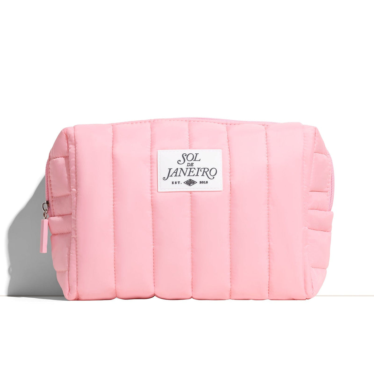 Pink quilted pouch with a brand label on a white background