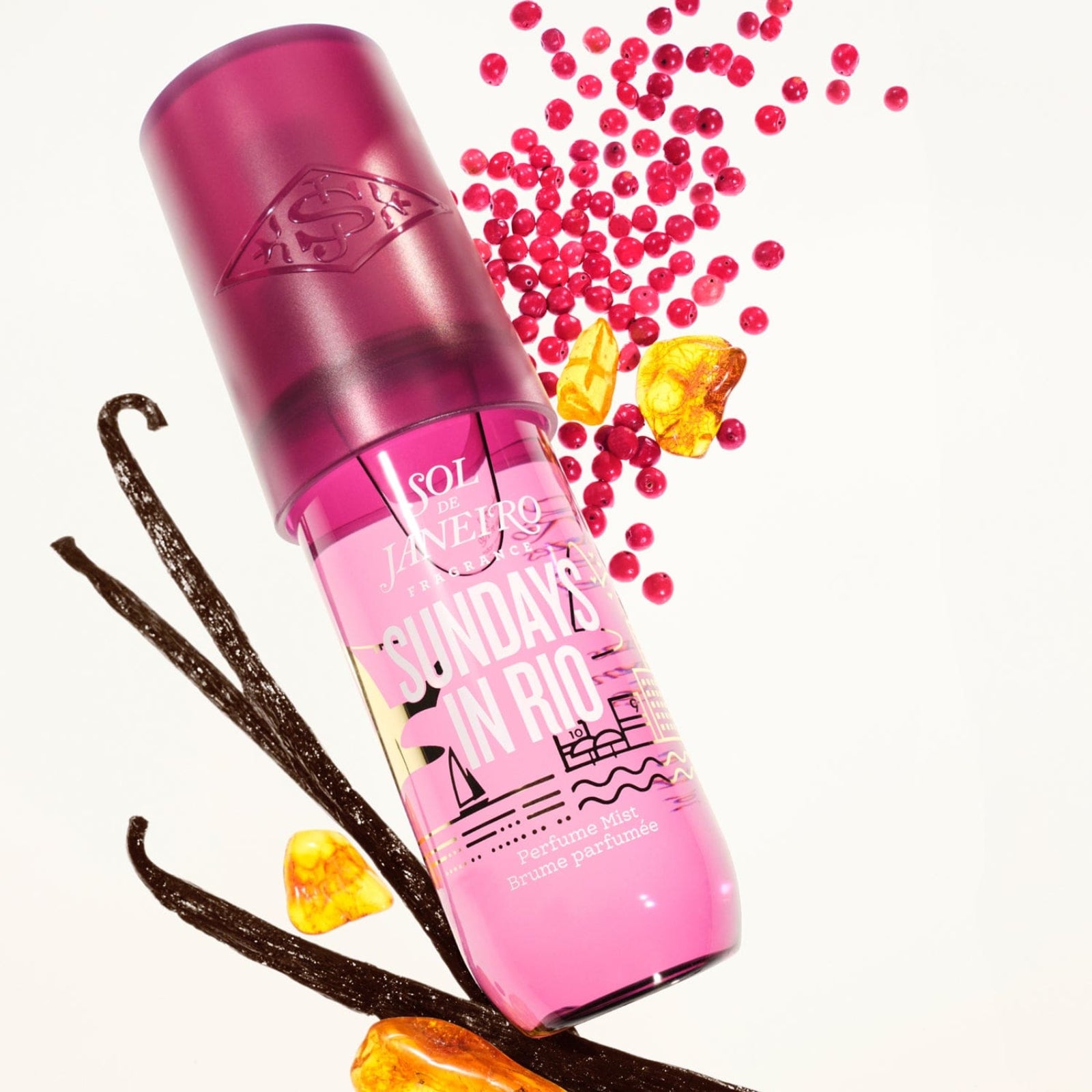 Pink bottle labeled 'Sundays in Rio' with vanilla beans and pink beads on a white background