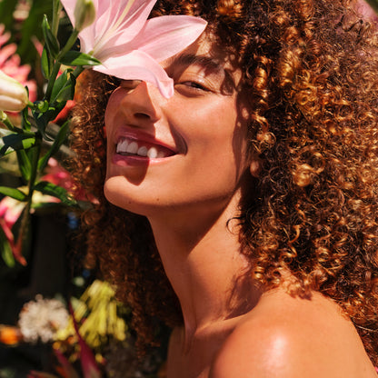 Curly haired model smiling with pink flowers