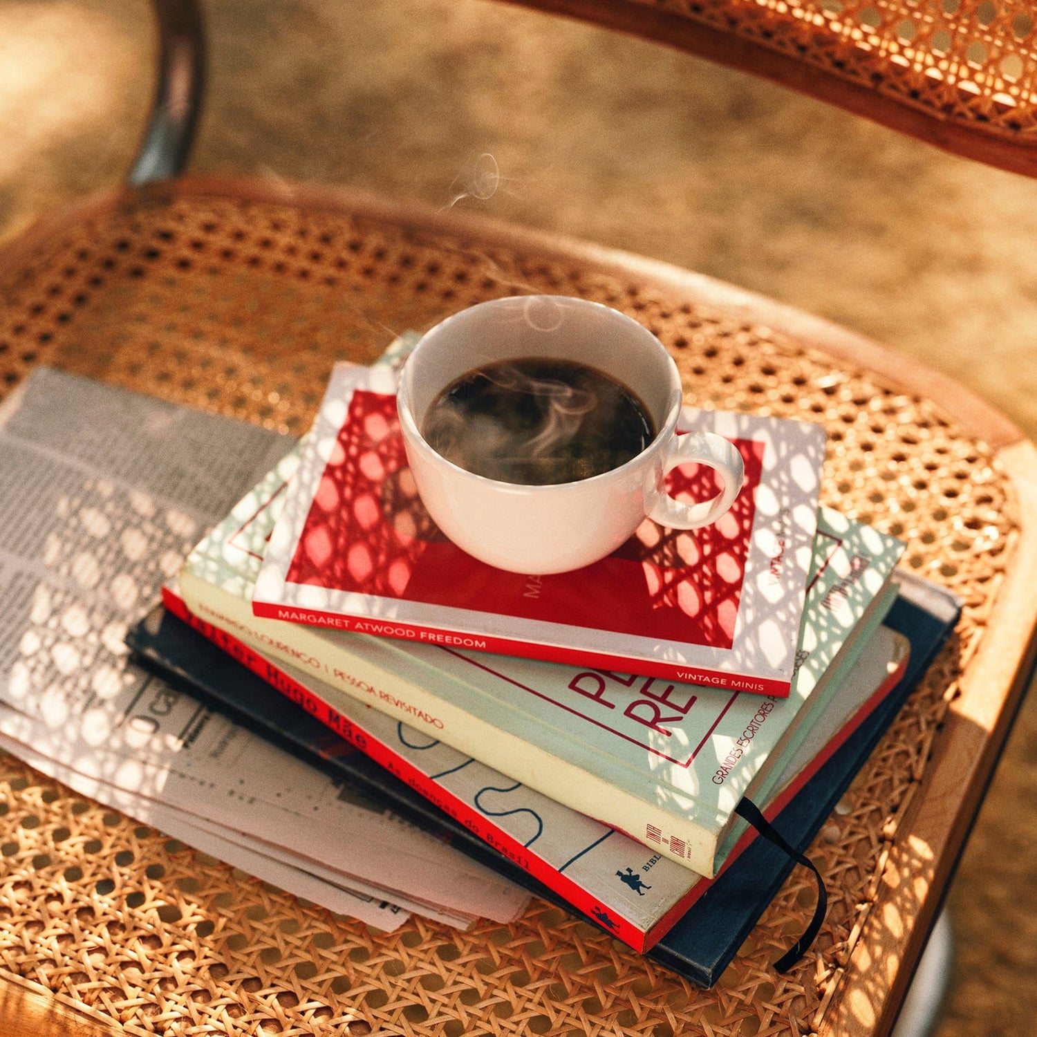 Warm cup of coffee on top of stack of books