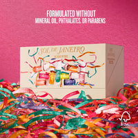 A boxed cosmetic set labeled SOL DE JANEIRO sits on a bed of colorful ribbon against a bright pink background. Text at the top reads 'FORMULATED WITHOUT MINERAL OIL, PHTHALATES, OR PARABENS.