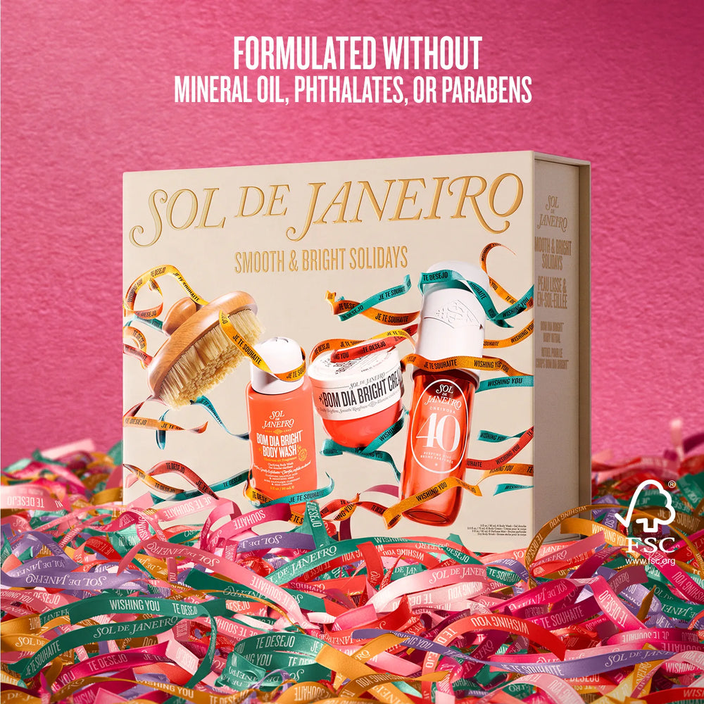 Sol de Janeiro Smooth & Bright Soldays gift set box displayed on a pink background with colorful ribbons around the base. The box features illustrations of skincare products and the brand name 'Sol de Janeiro' in gold lettering.
