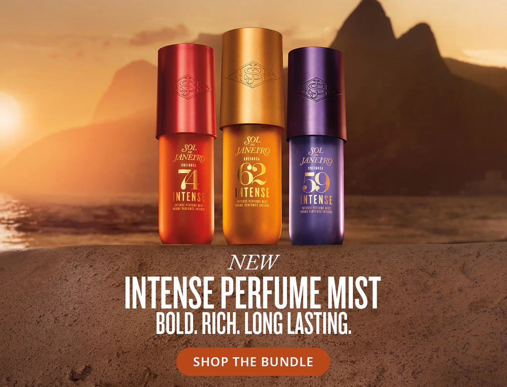 Three cylindrical perfume mist bottles from SDJ are displayed against a scenic sunset beach backdrop with mountains. The bottles are red, gold, and purple, labeled with intense scents.