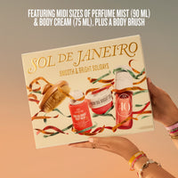 A gift set box held by two hands, featuring the brand name SOL DE JANEIRO and holiday-themed illustrations of a body brush, body cream, and body wash. The box is set against a warm gradient background with promotional text at the top.