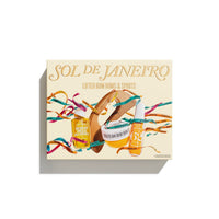 A square product box for 'SOL DE JANEIRO Lifted Bum Buns & Spirits' by The Happy Wench, featuring a cream-colored background with illustrations of a brown bun, a bun with a strawberry, and two orange-brown bottles surrounded by colorful confetti ribbons.