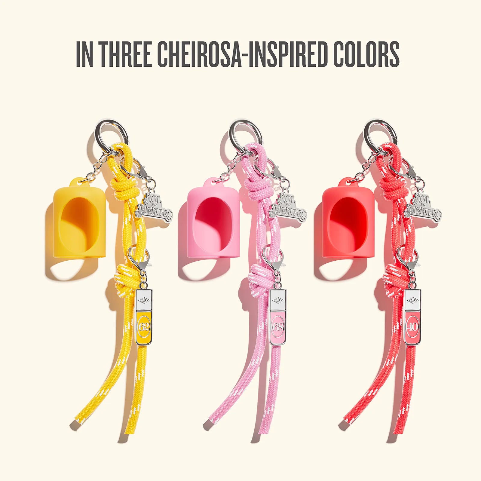 Three pet leash keychains in yellow, pink, and red-orange are displayed side by side on a light beige background with the text 'IN THREE CHEIROSA-INSPIRED COLORS' at the top.