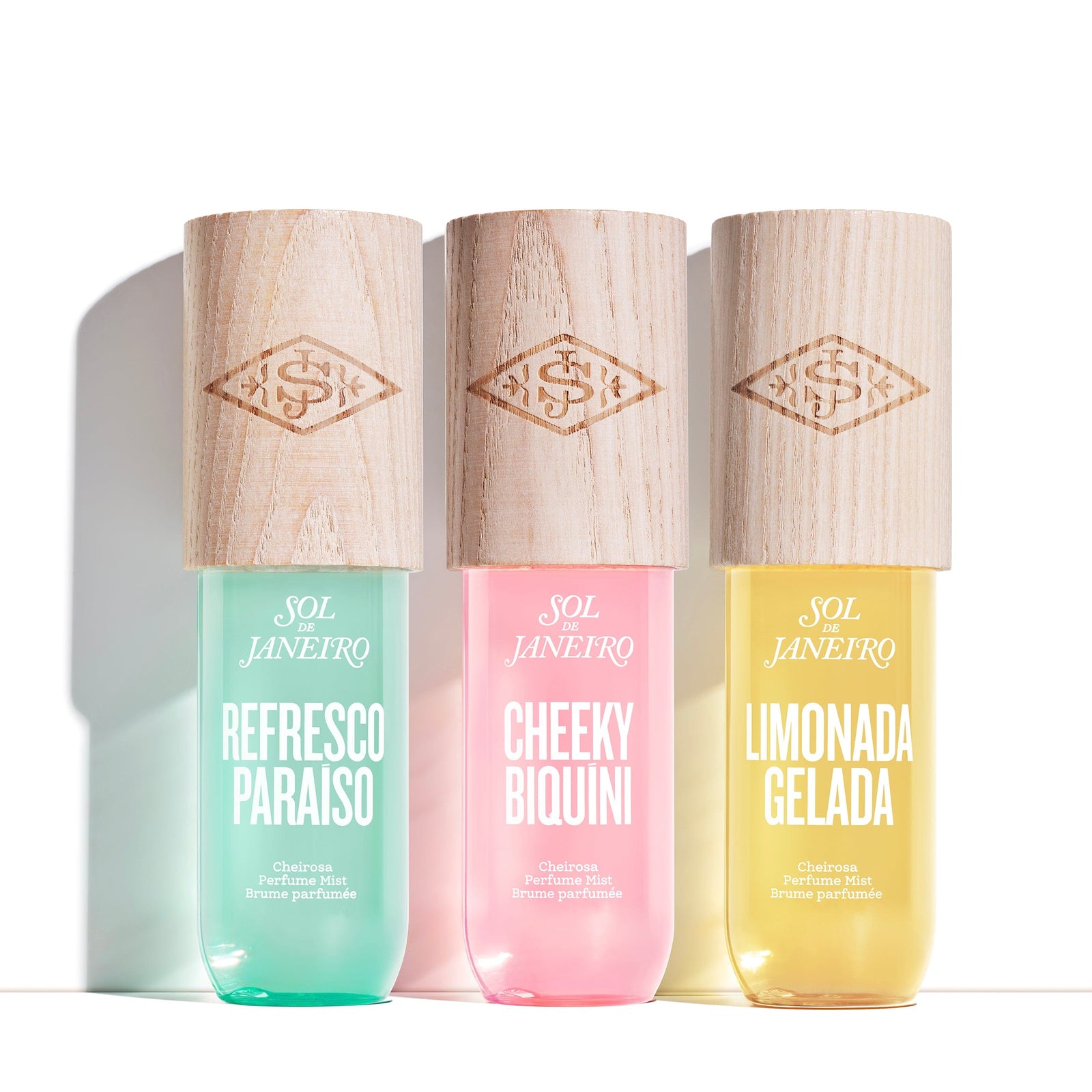 Three Sol de Janeiro perfume bottles with wooden caps on a white background
