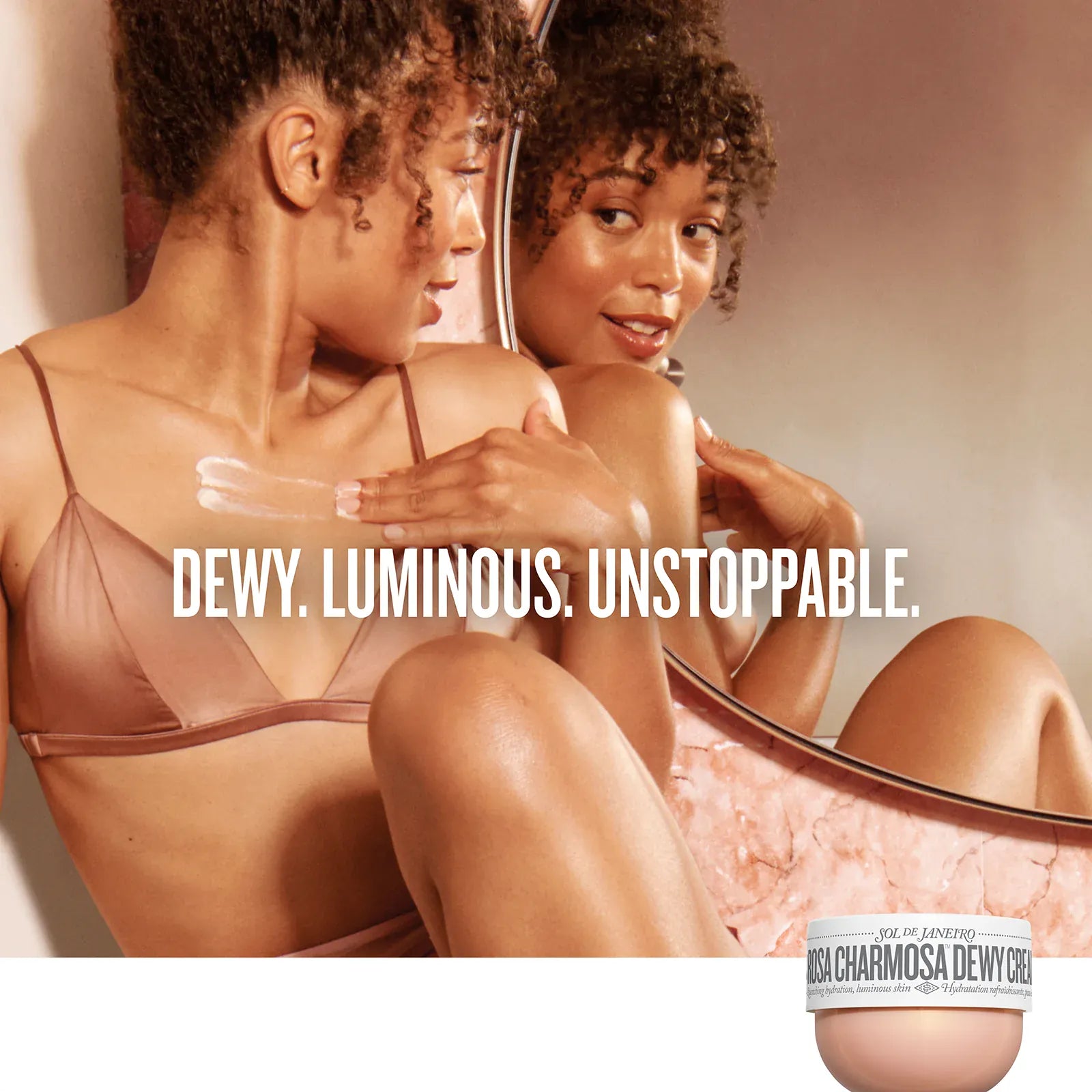Two women sitting together with a jar of cream labeled 'DEWY. LUMINOUS. UNSTOPPABLE.'