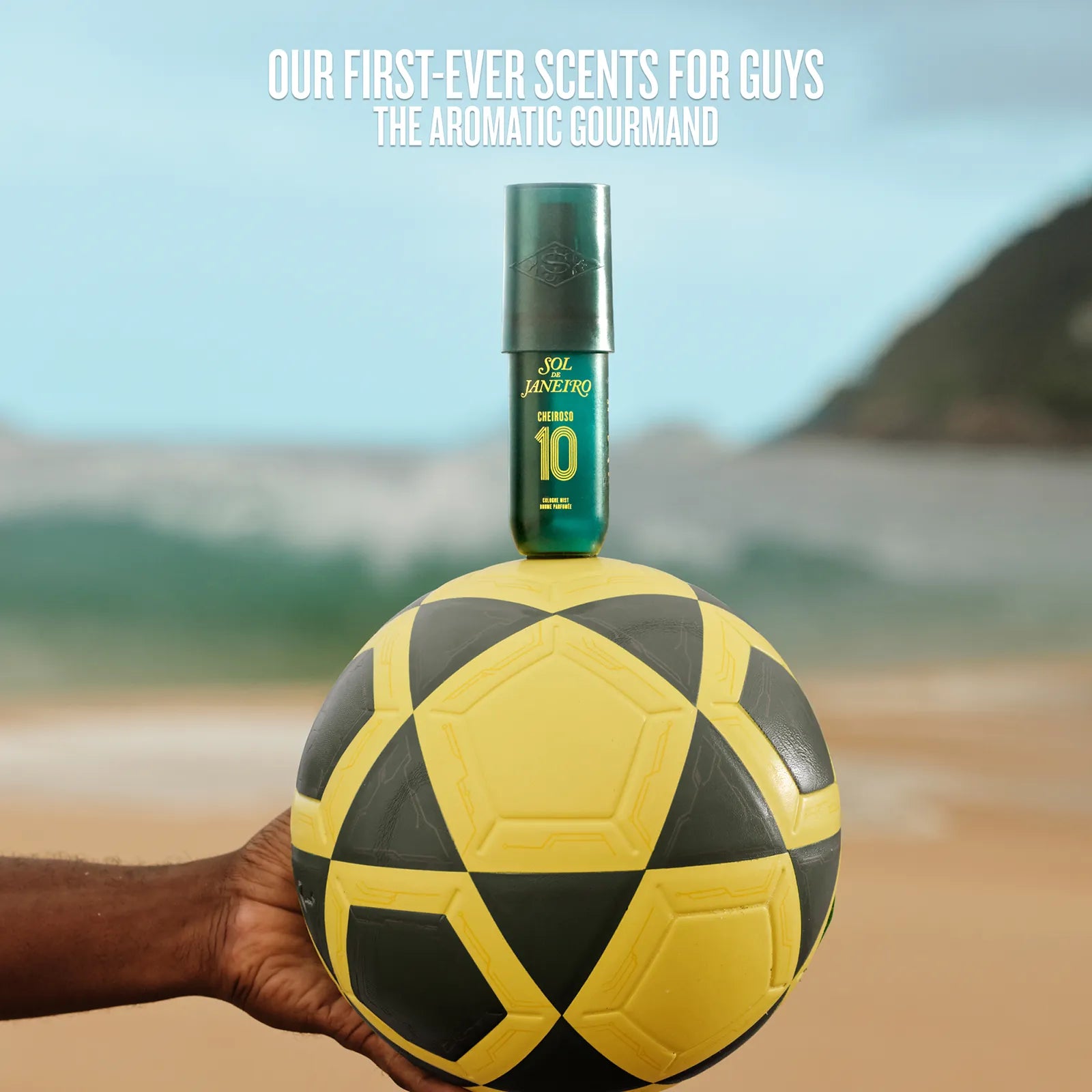 Scent bottle on a soccer ball held by a hand with beach background