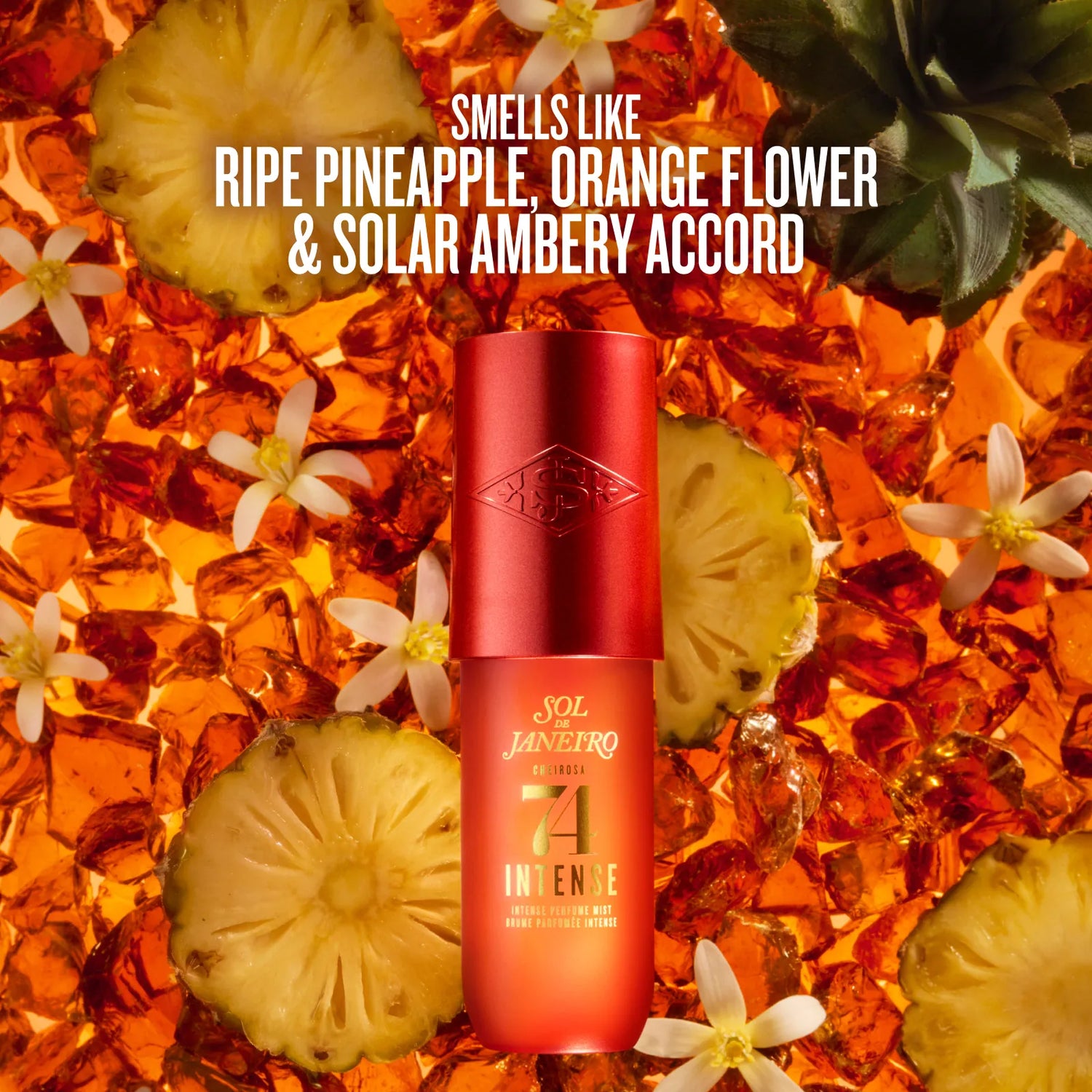 A red and orange cylindrical bottle of Sol Janeiro Intense sunscreen stands centered against a tropical background of sliced pineapple, white flowers, and amber liquid. White text at the top reads, &