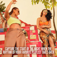 Two women posing outdoors in vibrant outfits against a colorful mosaic wall. One wears a lime green crop top and brown pants, while the other wears an orange and metallic bronze dress. The copy on image reads, CAPTURE THE START OF THE NIGHT WHEN THE RHYTHM OF YOUR FAVORITE PLAYLIST TAKES OVER