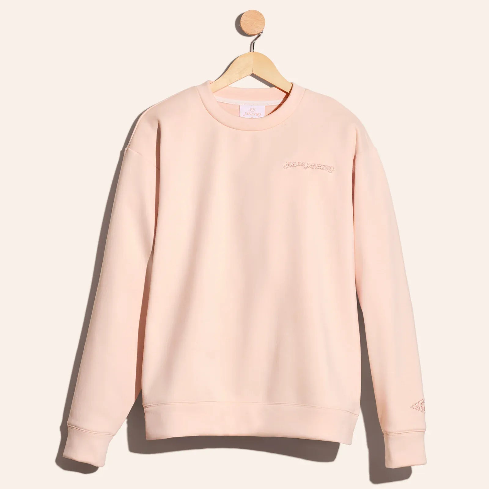 Beige sweatshirt on a hanger against a light gray background