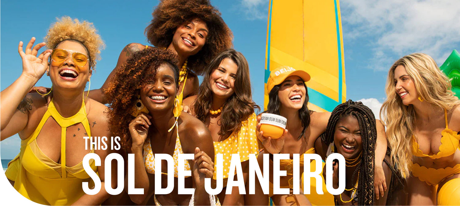 This is Sol de Janeiro - 7 women smiling in yellow swimwear with a blue sky background